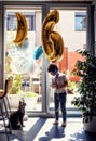 Toddler boy holding balloon in shape of figure six looking at his maine coon cat friend Royalty Free Stock Photo