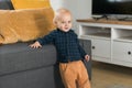 Toddler boy laughing having fun standing near sofa in living room at home copy space. Adorable baby making first steps Royalty Free Stock Photo