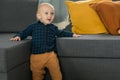 Toddler boy laughing having fun standing near sofa in living room at home copy space. Adorable baby making first steps Royalty Free Stock Photo