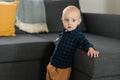 Toddler boy laughing having fun standing near sofa in living room at home copy space. Adorable baby making first steps Royalty Free Stock Photo