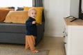 Toddler boy laughing having fun standing near sofa in living room at home copy space. Adorable baby making first steps Royalty Free Stock Photo