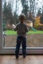 Toddler boy looking outside the window on a rainy day Royalty Free Stock Photo