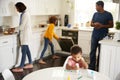 Toddler boy painting sitting at a table in the kitchen painting a pciture, his family busy in the background Royalty Free Stock Photo