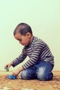 Toddler boy is playing in the house on the floor. A kid boy playing toy blocks inside his house. Happy little boy. Smiling child Royalty Free Stock Photo