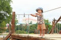 Toddler boy playing on playground - standing on bridge