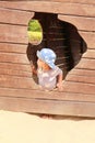 Toddler boy playing on playground - watching out from hole of boat