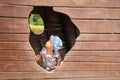 Toddler boy playing on playground - watching out from hole of boat