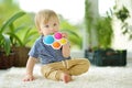 Toddler boy playing with rainbow pop-it fidget toy at home. Small child with stress and anxiety relief fidgeting game