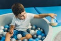 Toddler boy playing with a toy while sitting in a ball pit full of colorful balls. A ball pit - a great place for kids Royalty Free Stock Photo