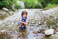 Toddler boy plays with stick in flashy river