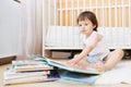 Toddler boy reading books against white bed Royalty Free Stock Photo