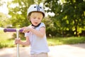 Toddler boy in safety helmet learning to ride scooter Royalty Free Stock Photo