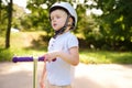 Toddler boy in safety helmet learning to ride scooter Royalty Free Stock Photo