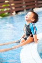 Asian boy sitting and laughing on the edge of a swimming pool Royalty Free Stock Photo