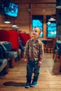 toddler boy standing in cafe restaurant looking at TV set channel program.