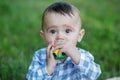 Toddler boy is teething. Baby gnaws toy while walking in park. Concept of childhood and nursery Royalty Free Stock Photo