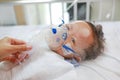 Toddler boy using nebulizer to cure asthma or pneumonia disease . Sick baby boy rest on patients bed and has inhalation therapy