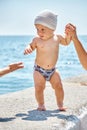 Toddler boy walking on stone pier looks incredulously at woman