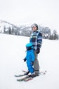 Toddler boy in warm blue overalls, helmet learns to ski with his dad Royalty Free Stock Photo
