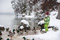 Toddler boy in warm winter suit feeding ducks
