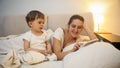 Adorable toddler boy watching as his mother using digital tablet in bed Royalty Free Stock Photo