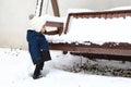 Toddler boy watching garden swing covered with snow