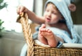 A toddler boy sitting on the wicker chair in the bathroom at home.