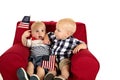 Toddler boys sitting in a red chair holding American flags Royalty Free Stock Photo