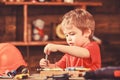 Toddler on busy face plays with bolts at home in workshop. Kid boy play as handyman. Handcrafting concept. Child cute