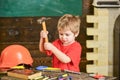 Toddler on busy face plays with hammer tool at home in workshop. Child cute and adorable playing as builder or repairer Royalty Free Stock Photo