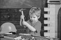 Toddler on busy face plays with hammer tool at home in workshop. Child cute and adorable playing as builder or repairer Royalty Free Stock Photo