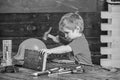 Toddler on busy face plays with hammer tool at home in workshop. Child cute and adorable playing as builder or repairer Royalty Free Stock Photo