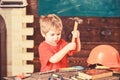 Toddler on busy face plays with hammer tool at home in workshop. Child cute and adorable playing as builder or repairer Royalty Free Stock Photo