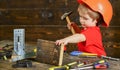 Toddler on busy face plays with hammer tool at home in workshop. Kid boy play as handyman. Handcrafting concept. Child Royalty Free Stock Photo