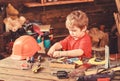 Toddler on busy face plays with tools at home in workshop. Kid boy play as handyman. Child cute and adorable playing