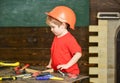 Toddler on busy face plays at workshop near table with tools. Workshop and tools concept. Kid boy playing with