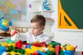 Toddler child boy playing with toys developing and learning activities. Cute child is sitting at a desk indoors. Child