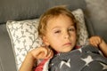 Toddler child with conjuctivitis, lying in bed with red eyes, inflamation of the eye disease