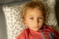 Toddler child with conjuctivitis, lying in bed with red eyes, inflamation of the eye disease