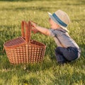 Toddler child outdoors. One year old baby boy wearing straw hat looking in picnic basket Royalty Free Stock Photo