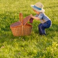 Toddler child outdoors. One year old baby boy wearing straw hat looking in picnic basket Royalty Free Stock Photo