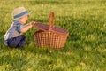 Toddler child outdoors. One year old baby boy wearing straw hat looking in picnic basket Royalty Free Stock Photo