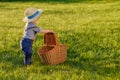 Toddler child outdoors. One year old baby boy wearing straw hat looking in picnic basket Royalty Free Stock Photo