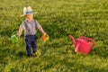 Toddler child outdoors. One year old baby boy wearing straw hat using watering can Royalty Free Stock Photo