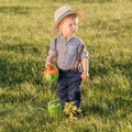 Toddler child outdoors. One year old baby boy wearing straw hat using watering can Royalty Free Stock Photo