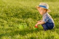 Toddler child outdoors. One year old baby boy wearing straw hat using watering can Royalty Free Stock Photo