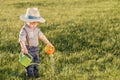 Toddler child outdoors. One year old baby boy wearing straw hat using watering can Royalty Free Stock Photo