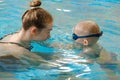 Toddler child trained to swim in indoor swimming pool