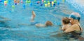 Toddler child trained to swim in indoor swimming pool