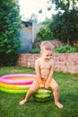 Toddler cute Caucasian white European race boy sitting hugging holding huge watermelon and smiling on background of green grass,